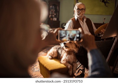 Senior man painting with his dog while being photographed at home - Powered by Shutterstock