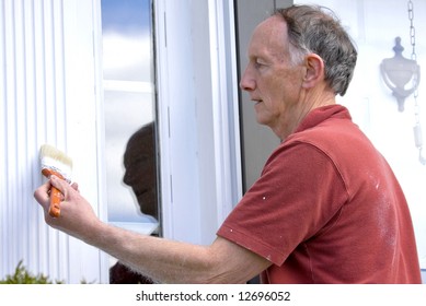 Senior Man Painting Outside Of House