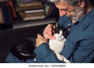 Senior Man Petting His Cat On A Sofa At Home