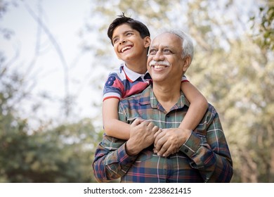 Senior man piggybacking grandson in park during weekend. - Powered by Shutterstock