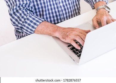 Senior man in plaid shirt typing on a gray laptop. Teleworking concept. - Powered by Shutterstock