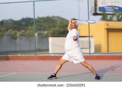 Senior man playing badminton outdoor at badminton court. Concept of active lifestyle being on pension - Shutterstock ID 2256103291