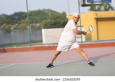 Senior man playing badminton outdoor at badminton court. Concept of active lifestyle being on pension - Shutterstock ID 2256103295