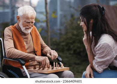 Senior man playing chess outdoors with his daughter.
