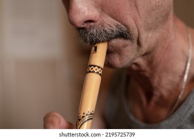 Senior Man Playing The Flute. Faceless Unprofessional Male Of Elderly Caucasian Recorder People With A Moustache With Mouth And Lips Play On Pipe Amateur Music Close Up At Home. Hobbies And Leisure