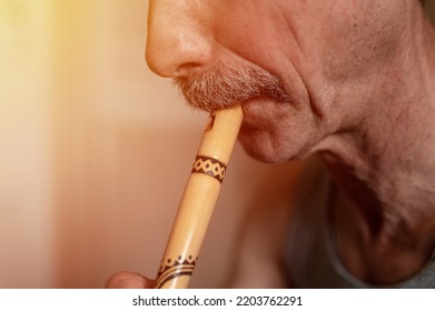 Senior Man Playing The Flute. Faceless Unprofessional Male Of Elderly Caucasian Recorder People With A Moustache With Mouth And Lips Play On Pipe Amateur Music Close Up At Home. Hobbies And Leisure