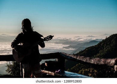 Senior man playing guitar among sea of mist in the morning.  - Powered by Shutterstock