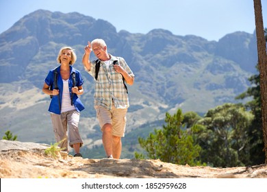 Senior Man Pointing The Route Of The Hike To His Wife As They Walk