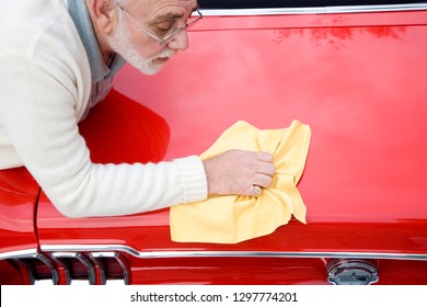 Senior Man Polishing Paintwork Of Classic Sports Car