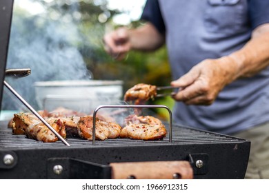 Senior man preparing barbecue grill for garden party. Selective focus at grilled chicken meat - Powered by Shutterstock