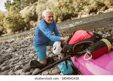 Senior man preparing for kayak tour on a mountain river. - Powered by Shutterstock