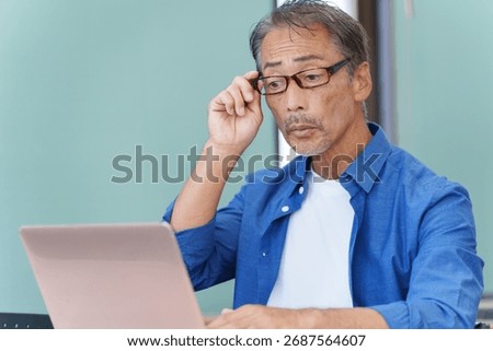 A senior man with presbyopia using a computer