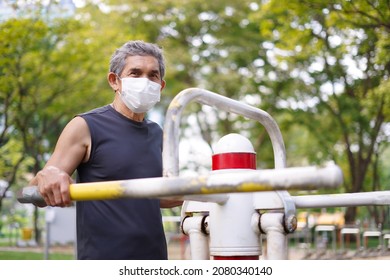 An Senior Man With Protective Face Mask Doing Exercise At Outdoor Fitness Equipment In The Public Park, Concept Health Care In Elderly People, Lifestyle    