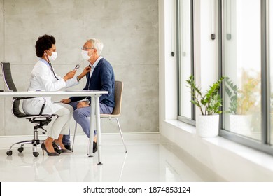 Senior Man With Protective Facial Mask Receive News From Black Female Doctor In The Office