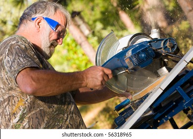 Senior Man in Protective Goggles Cutting Wood with a Chop Saw. - Powered by Shutterstock