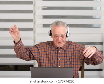 Senior man raised hands up and listen music from laptop