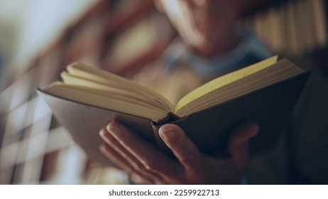 Senior man reading a book in public library, turning pages, doing research - Powered by Shutterstock