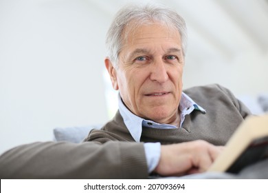 Senior man reading book relaxed in sofa