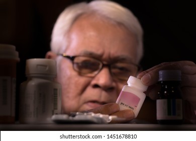 Senior Man Reading Drug Prescription On Drug Bottle