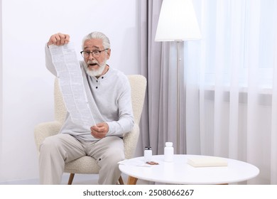 Senior man reading medicine instruction in armchair at home - Powered by Shutterstock