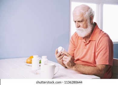 Senior Man Reading Recommendations On Bottle Of Tablets