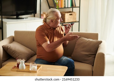 Senior Man Recording Voice Message For His Friend Or Family Member When Drinking Tea In Living Room