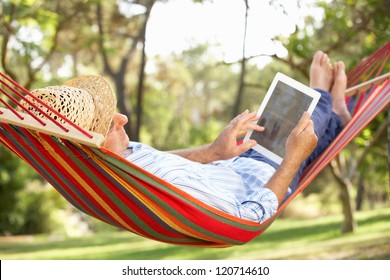 Senior Man Relaxing In Hammock With  E-Book - Powered by Shutterstock