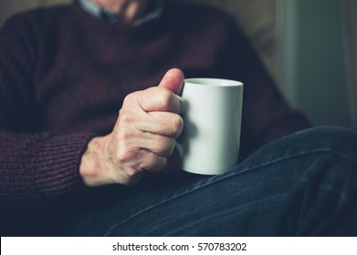 A senior man is relaxing at home with a mug of tea - Shutterstock ID 570783202