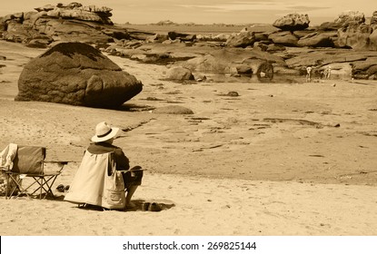 Senior man relaxing at Pink Granite Coast (Brittany, France) and looking at his grandchildren playing. Family summer vacation background. Aged photo. Sepia.  - Powered by Shutterstock