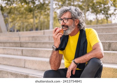 senior man rests eating an apple after workout - Powered by Shutterstock