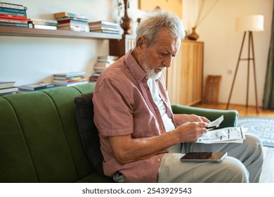 Senior man reviewing utility bills at home with concern - Powered by Shutterstock