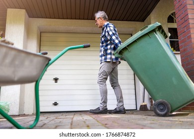 Senior Man Rolling Garbage Can
