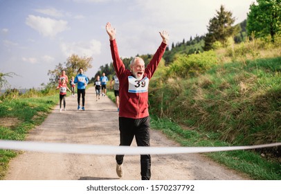 Senior Man Runner Crossing Finish Line In A Race Competition In Nature.