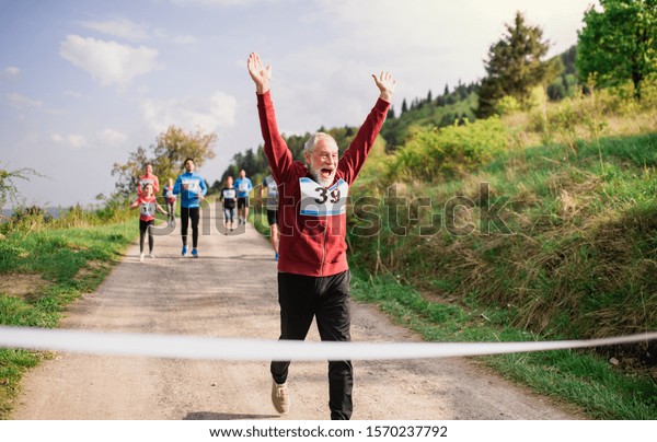 Senior man runner crossing finish line in a race\
competition in nature.