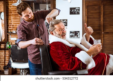 The senior man in Santa claus costume shaving his personal master at barber shop before Christmas - Powered by Shutterstock