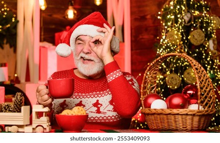 Senior man Santa claus drinking tea. New year. Grandpa with mug. Cozy interior. Christmas eve treats. Winter holiday. Christmas cocoa recipe. Garland lights cozy atmosphere. Cozy home. Hot beverage - Powered by Shutterstock