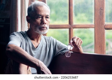 The Senior Man Sat In An Armchair And Looked Through The Window. A Lonely Old Man Sitting At Home Near The Window. Contemplative Retired Man