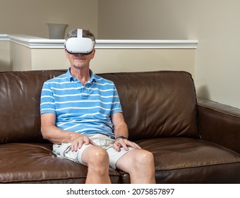 Senior man seated and watching an app on a modern virtual reality VR headset in home