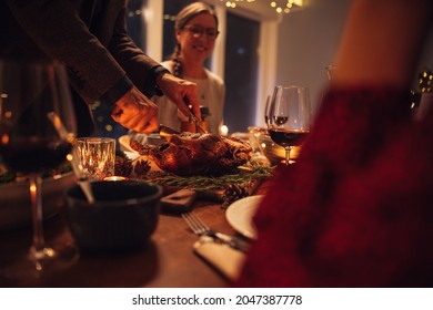 Hombre mayor que sirve pavo asado rellenado tradicional a la familia sentado en la mesa de la cena. Familia cenando Navidad en casa.