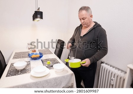 Senior man setting the table at home. Household chores in older age, active retirement, shared domestic responsibilities and gender equality in everyday life.