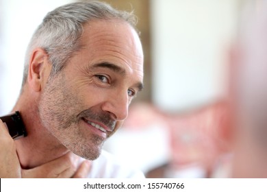 Senior Man Shaving Beard With Electric Razor