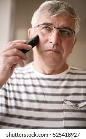 Senior Man Shaving At Home, Using Electric Razor. 