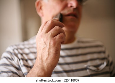 Senior Man Shaving At Home, Using Electric Razor.  Focus On Hand. 