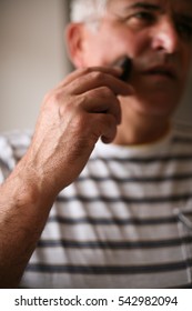 Senior Man Shaving At Home, Using Electric Razor.  Focus On Hand. 