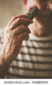 Senior Man Shaving At Home, Using Electric Razor.  Focus On Hand. 