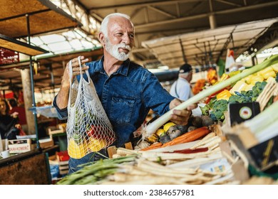 Senior man shopping at the farmer's market. One elderly man buying a fresh vegetable at a community marketplace. - Powered by Shutterstock