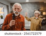 senior man sing karaoke on microphone with senior woman dance behind