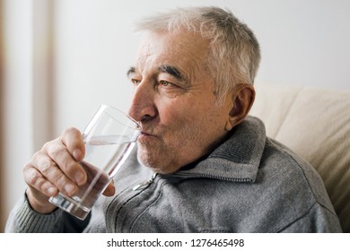 Senior Man Sitting By The Window Drinking Water Taking Medicine