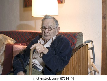 A senior man sitting and holding his cane.