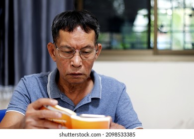 senior man sitting at home reading a book In order to relax due to the corona virus (Covid 19) is spreading, you must protect yourself from going to the mall.
